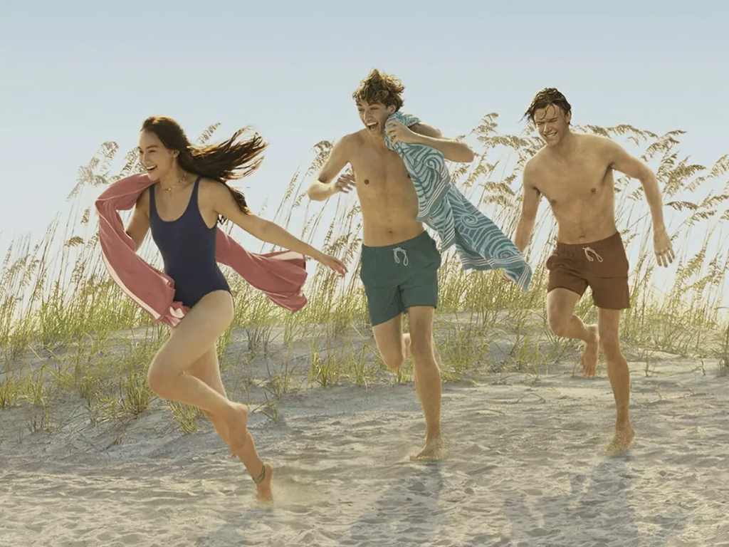 imagem de divulgação da série O Verão Que Mudou Minha Vida, com os atores principais correndo na praia